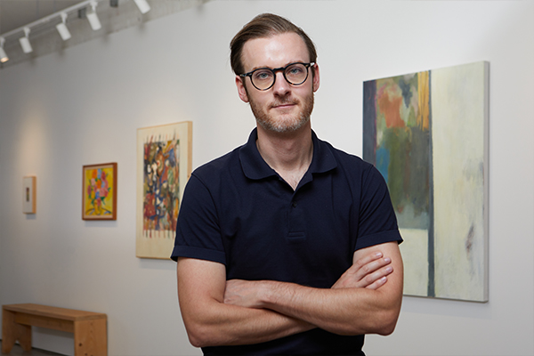 Man with his arms crossed standing in front of art work