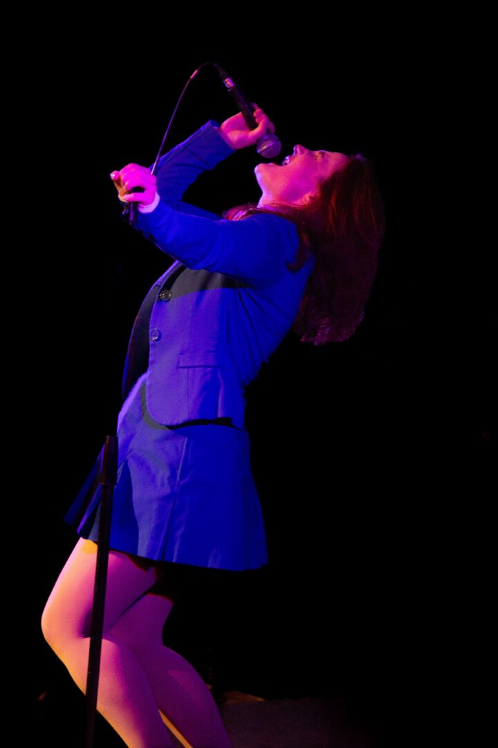 Gallery 3 - A singer (Aveleigh Keller) looking up to the sky as she's singing into a microphone.